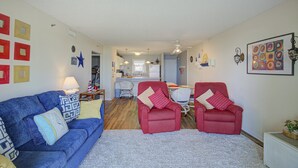 Ein Wohnzimmer mit einem blauen Sofa, roten Sessel und einem weißen Teppich.