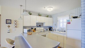 Eine Küche mit weißen Schränken, einer zentralen Kochinsel und einer Mikrowelle.