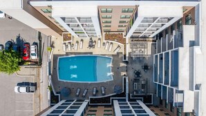 An aerial view of a hotel with a central swimming pool surrounded by sun loungers and a covered seating area. - The Nash Luxe- In the heart of Nashville (Nashville)