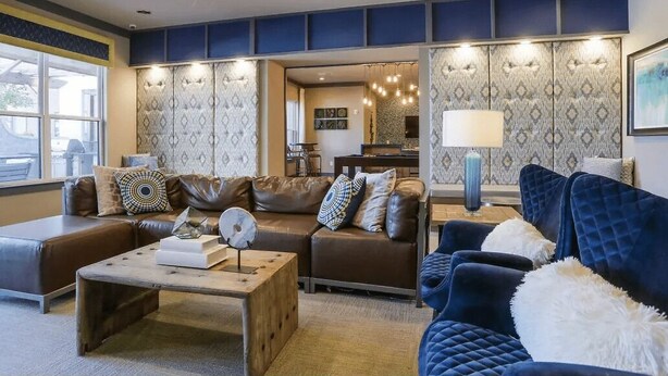 A modern living room with a brown leather sofa, a blue velvet armchair, and a wooden coffee table. - The Nash Luxe- In the heart of Nashville (Nashville)