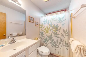 Ein Badezimmer mit Waschbecken, Spiegel und Toilette. Ein Handtuchhalter mit Handtuch ist vorhanden.