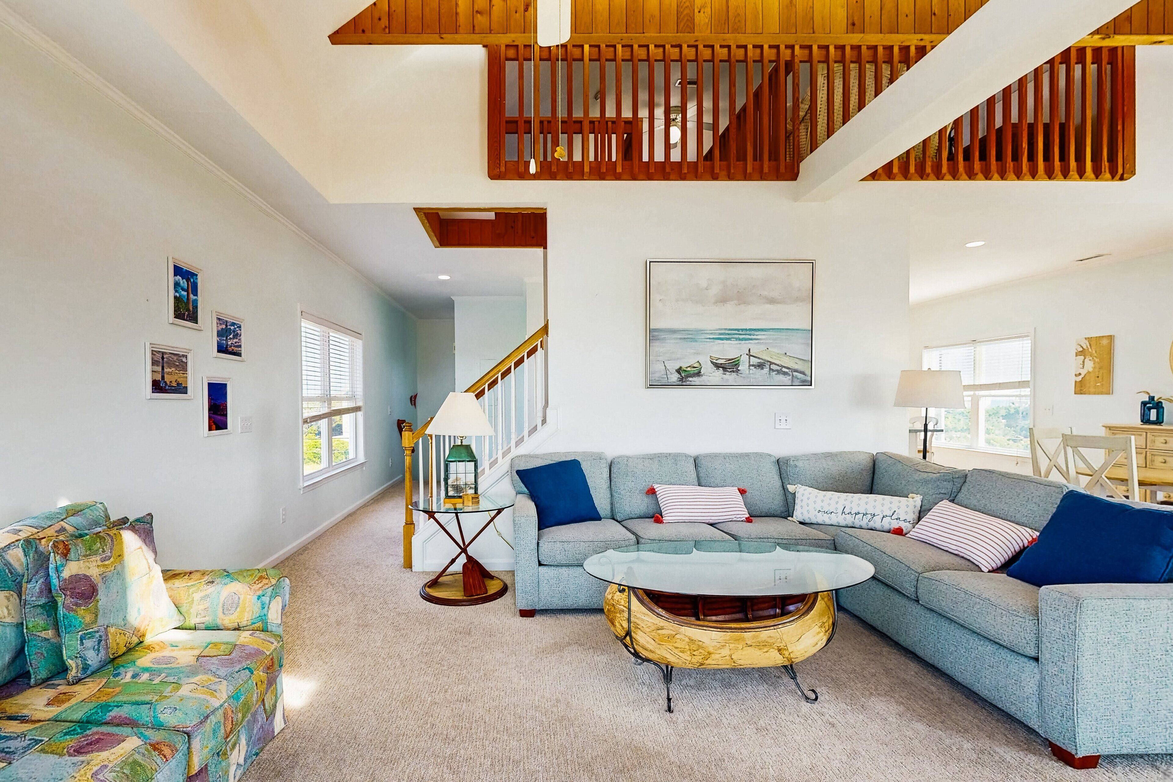 A spacious living room with a large sectional sofa, a coffee table, and a staircase leading to an upper level.