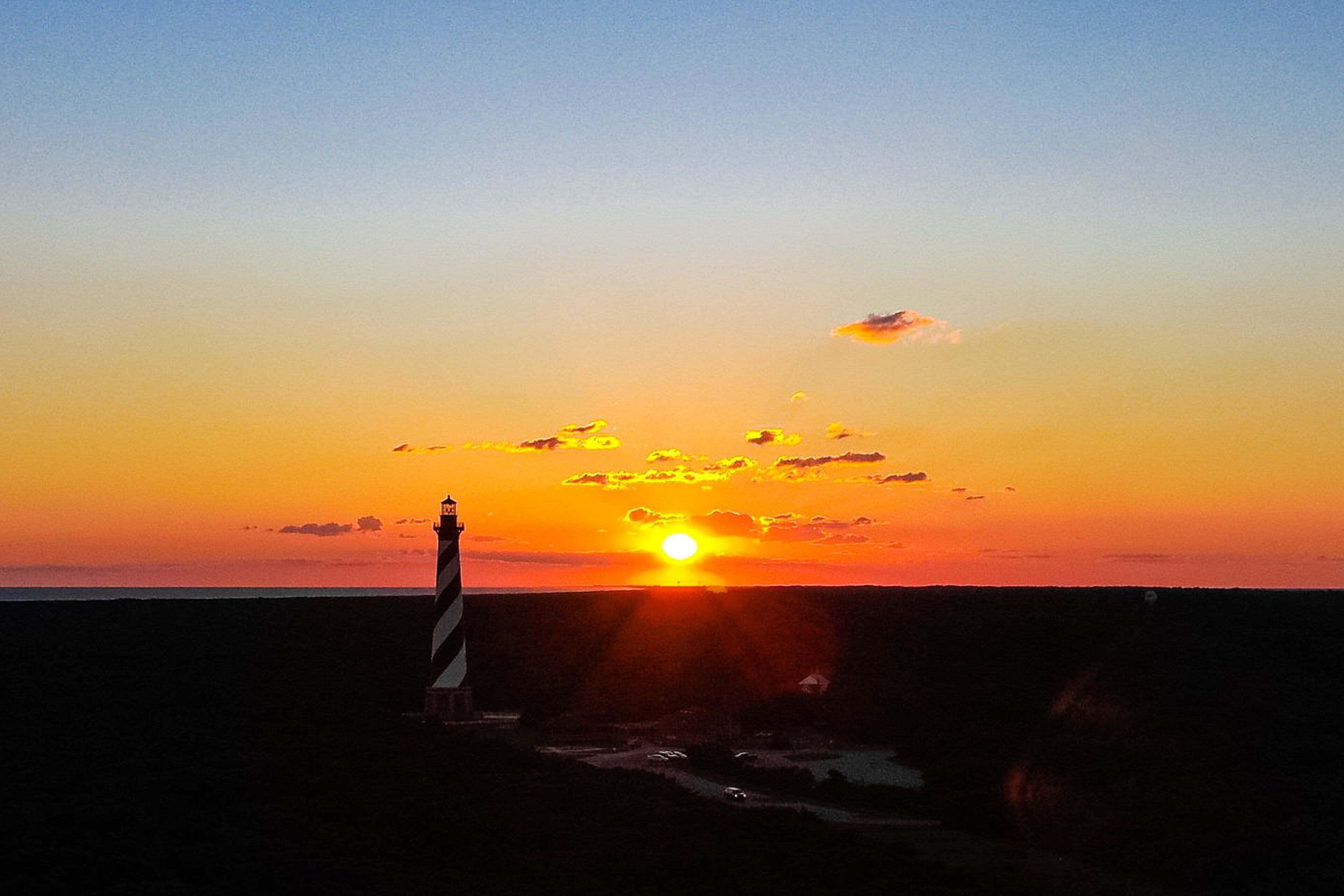 A sunset over a coastal area with a lighthouse.