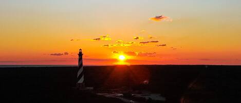 A sunset over a coastal area with a lighthouse.