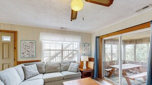 A cozy living room with a sectional sofa, a wooden coffee table, and a dining area with picnic tables. - Pelican's Roost 467: Semi-oceanfront, dog-friendly, outdoor pool/tennis (Avon)