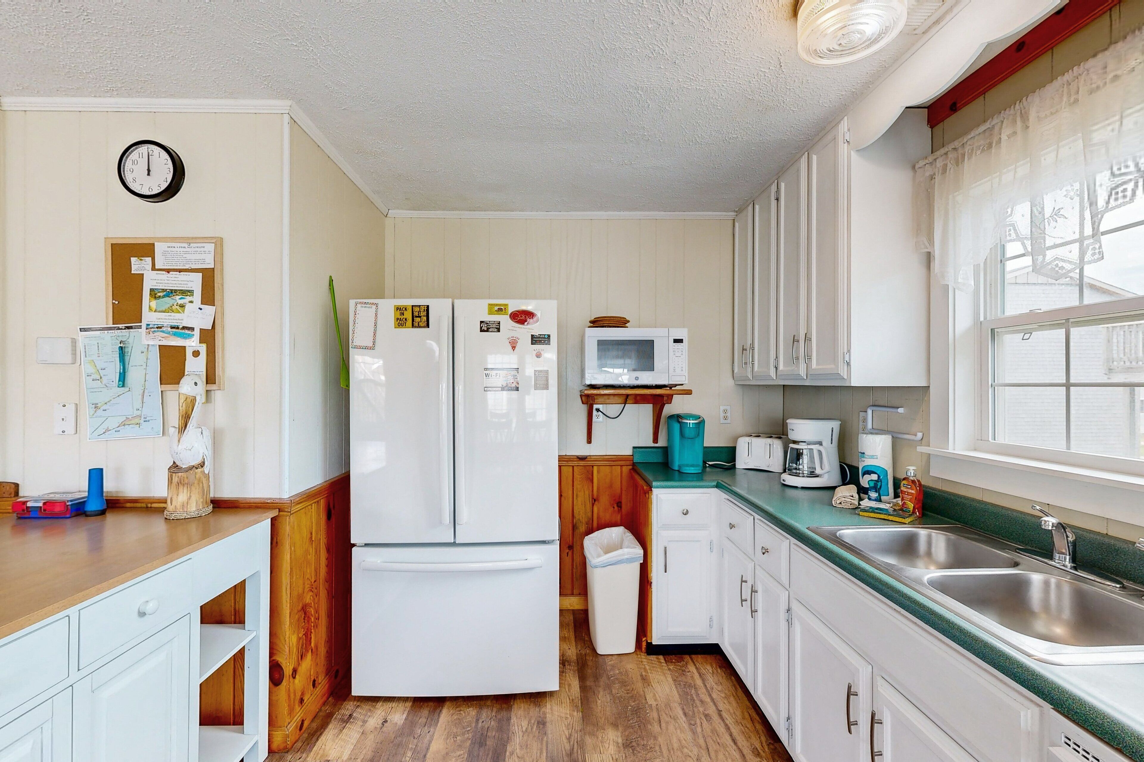 A compact kitchen with a refrigerator, microwave, sink, and wooden cabinets.