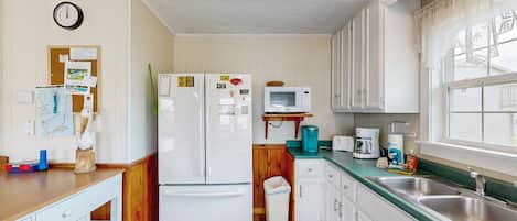 A compact kitchen with a refrigerator, microwave, sink, and wooden cabinets.