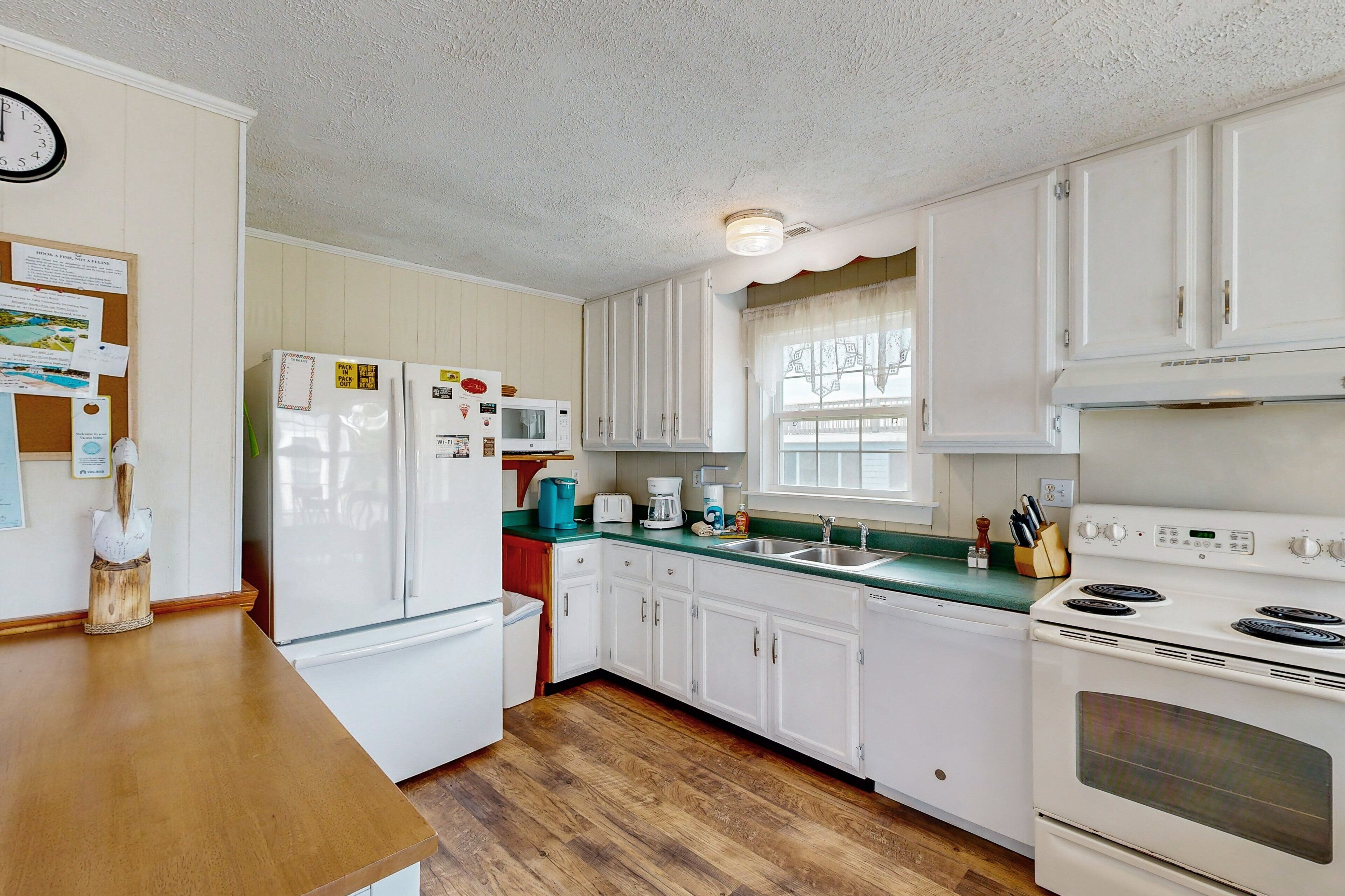 A kitchen with white cabinets, a microwave, a stove, and a sink.
