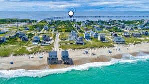 An aerial view of a coastal town with a beach, houses, and a bridge in the distance. - Stunning sound-front home with private hot tub, outdoor pool, & beach access (Rodanthe)
