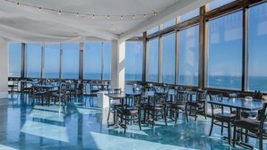 A spacious dining area with large windows offering ocean views, modern furniture, and a polished floor. - St. Regis beachfront condo with ocean & pool-view balcony, gym & sauna (North Topsail Beach)
