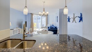 A modern kitchen with granite countertops, stainless steel sinks, and pendant lighting. - St. Regis beachfront condo with ocean & pool-view balcony, gym & sauna (North Topsail Beach)