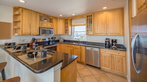 Una cocina moderna con armarios de madera, electrodomésticos de acero inoxidable y una isla grande con taburetes.