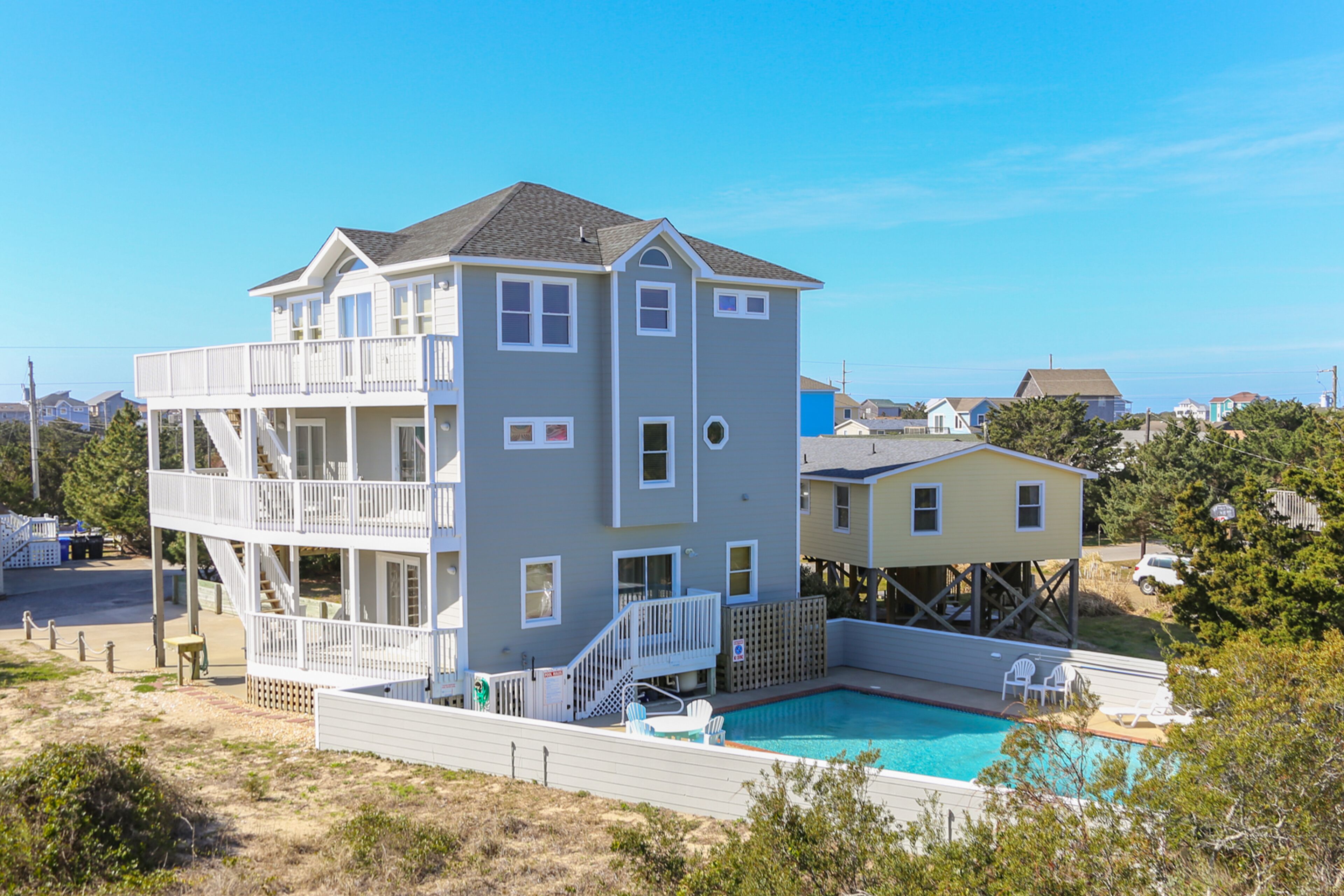 Une maison à deux étages dotée d’un balcon, d’une piscine et d’une terrasse.