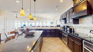 A spacious kitchen with dark wood cabinets, a large island, and pendant lighting. - Oceanfront estate - heated pool, pool spa, elevator, pool table & cook's kitchen (North Topsail Beach)