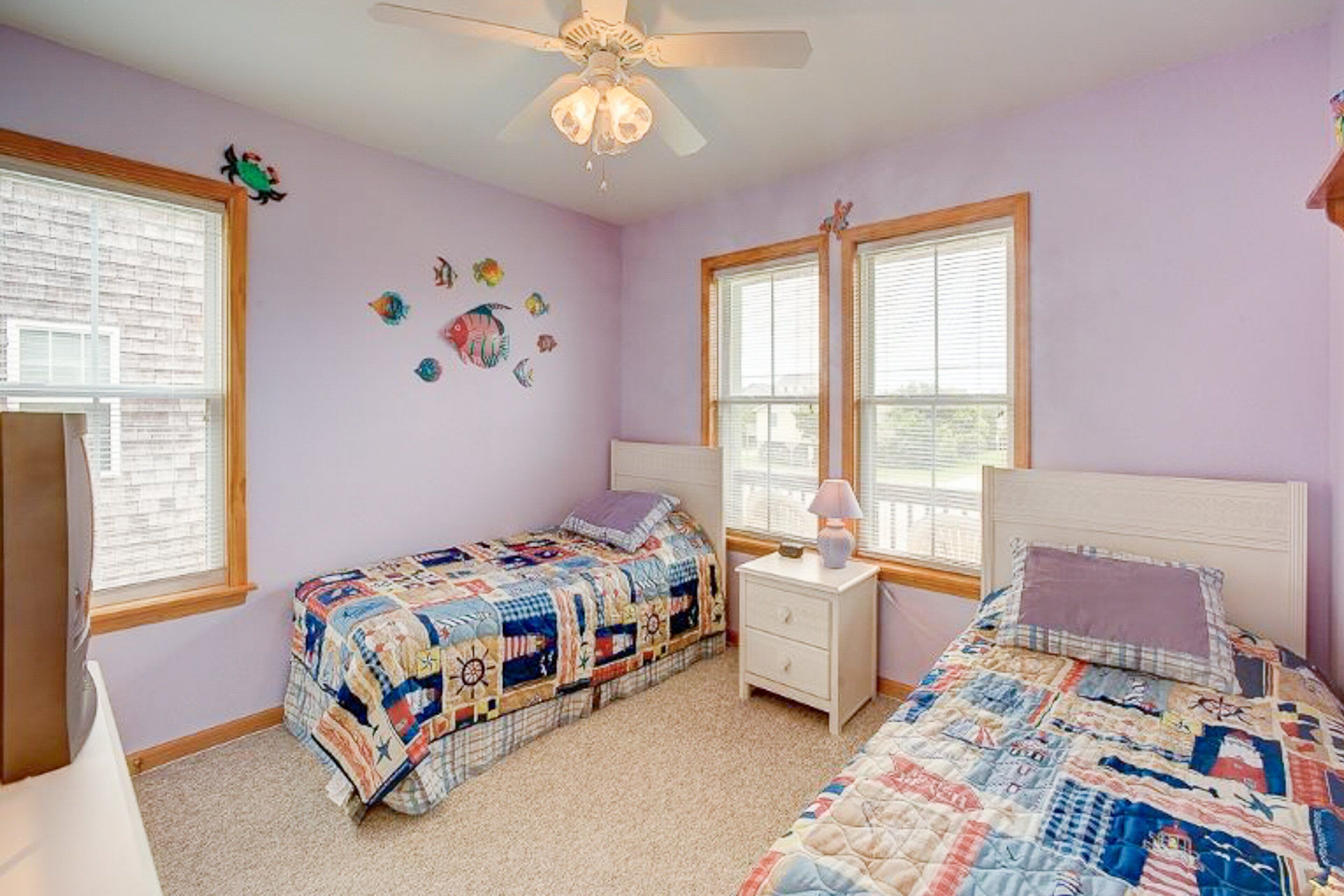A bedroom with two beds, a ceiling fan, and a window with blinds.