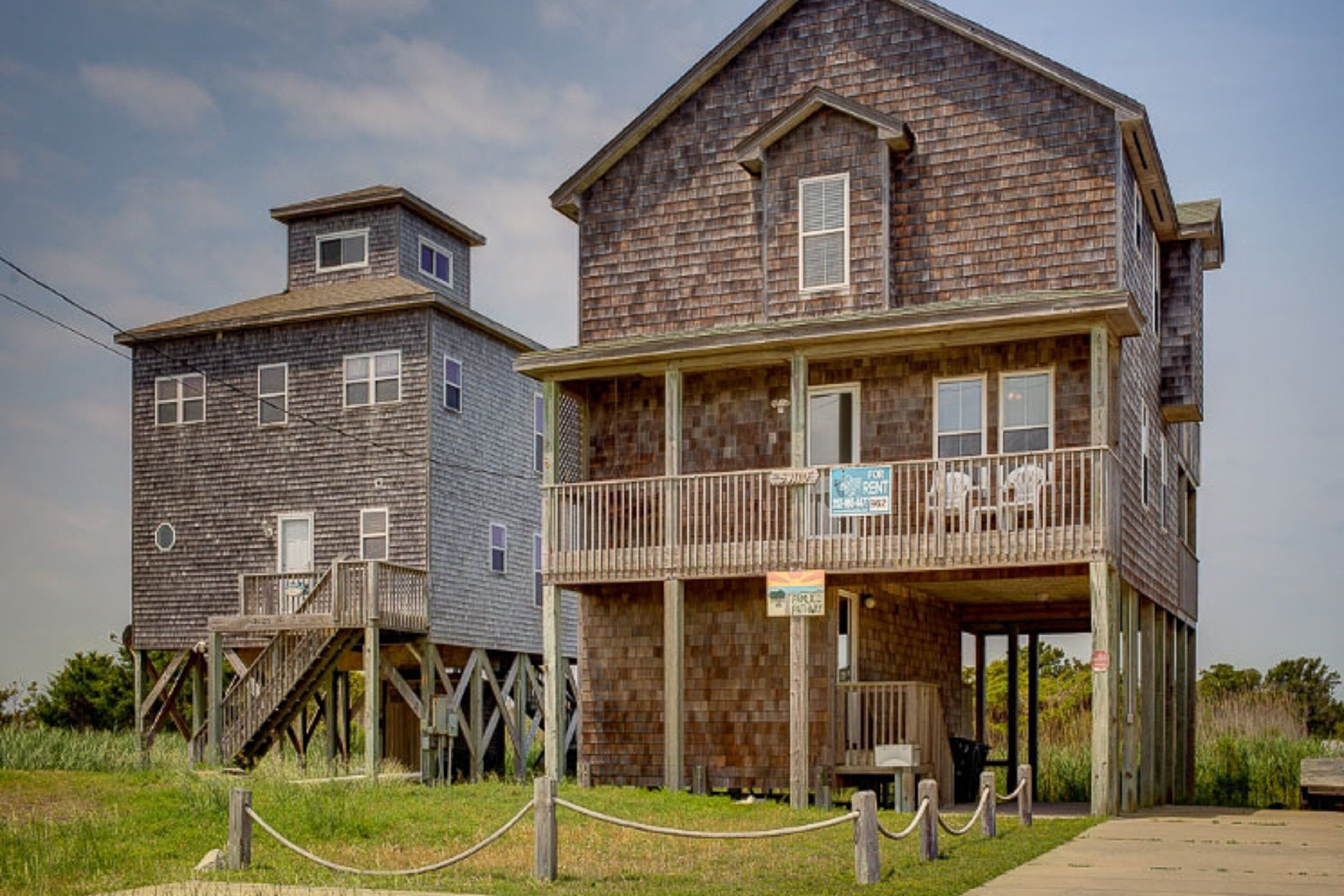 A wooden building with a balcony and a sign indicating it is for rent.