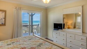 A bedroom with a bed, a dresser, a TV, and a balcony with a view of the ocean. - Oceanfront home with beach access, washer/dryer, central AC & golf nearby (North Topsail Beach)