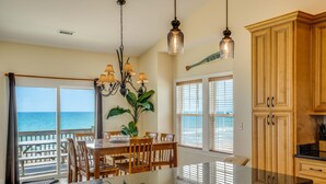 A kitchen with wooden cabinets, a granite countertop, and a dining area with a view of the ocean. - Oceanfront home with beach access, washer/dryer, central AC & golf nearby (North Topsail Beach)