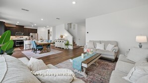 Een moderne woonkamer met een bank, salontafel en eethoek.