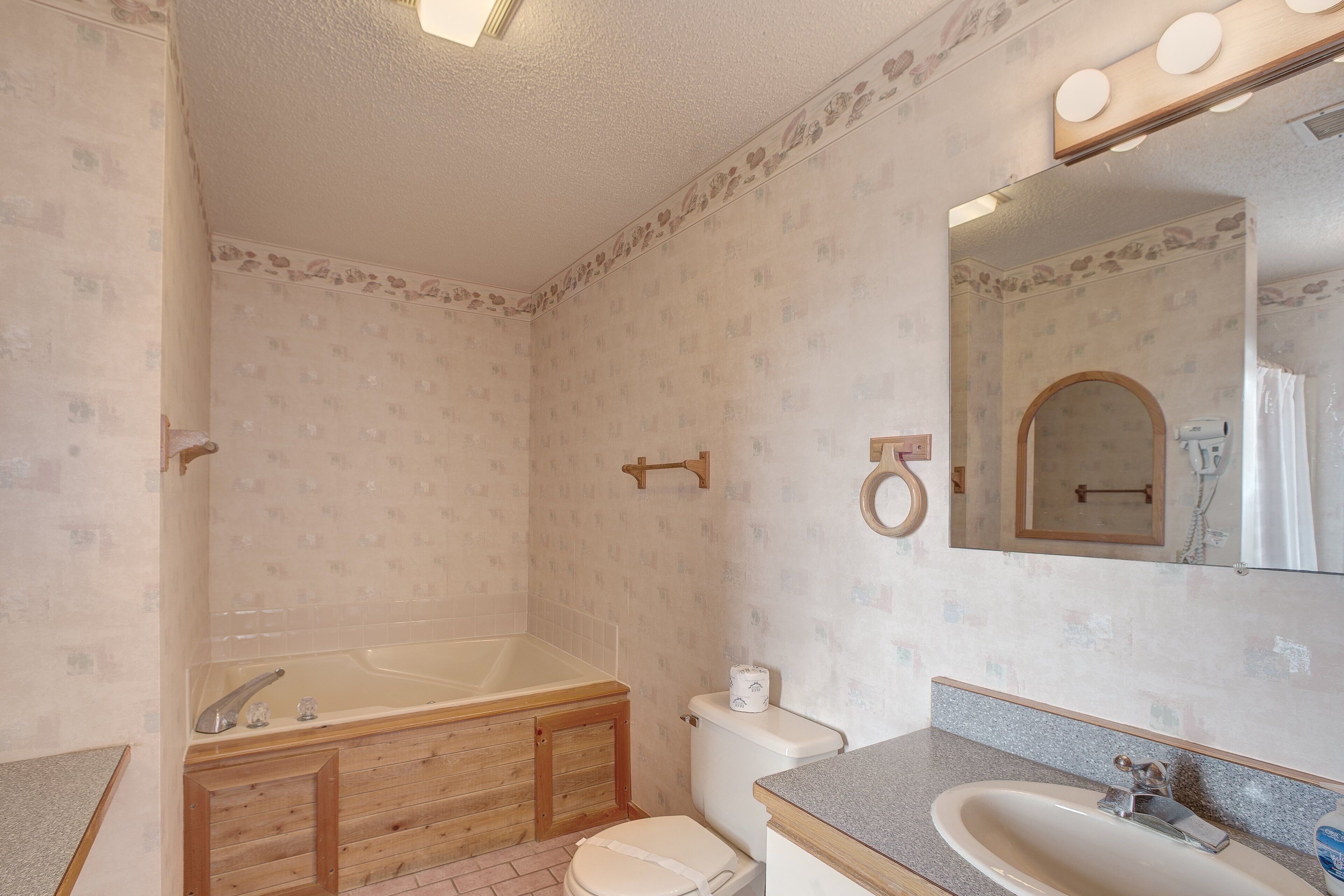 Une salle de bain équipée d’une baignoire, de toilettes, d’un lavabo et d’un miroir.
