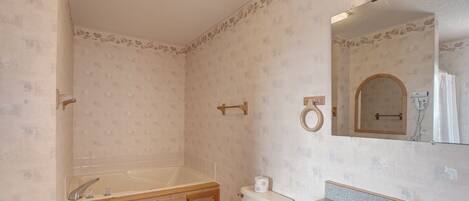 Une salle de bain équipée d’une baignoire, de toilettes, d’un lavabo et d’un miroir.