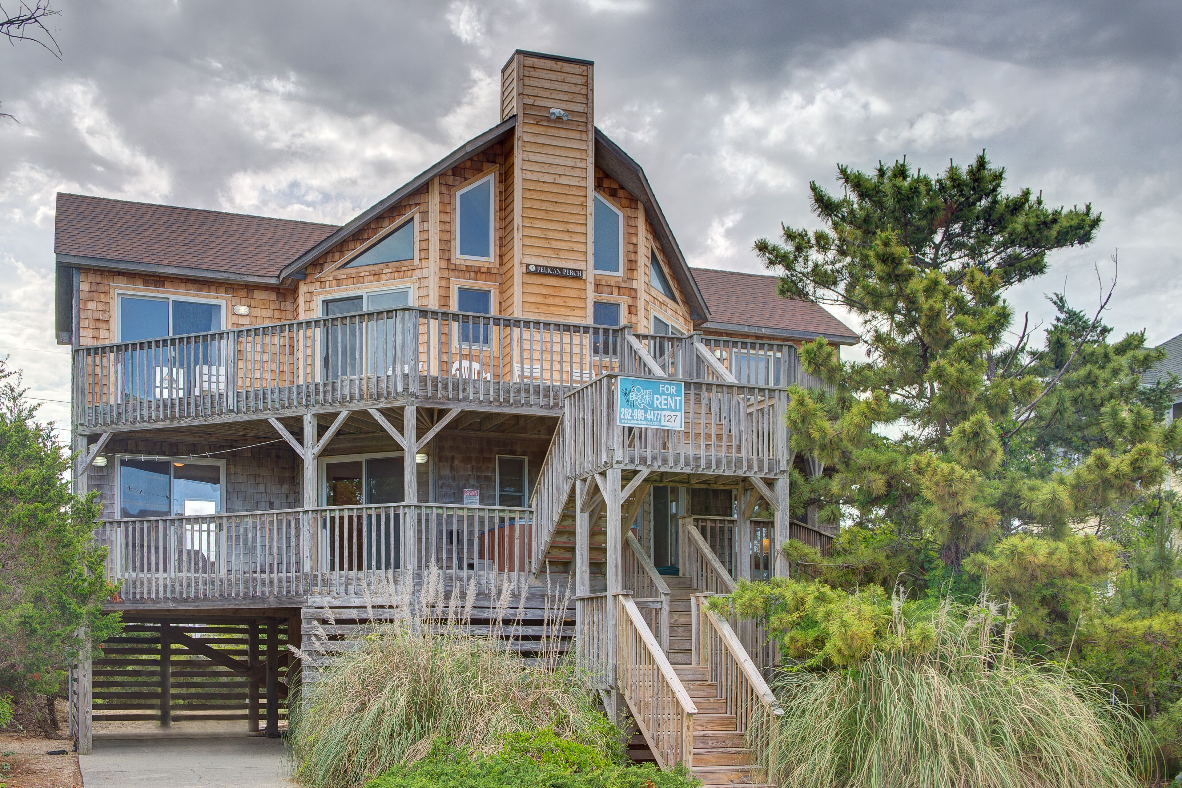 A wooden multi-story building with balconies and a sign indicating it is for rent.