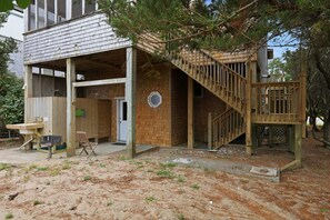 Een houten huis met een overdekte veranda, een trap en een klein zitgedeelte buiten.
