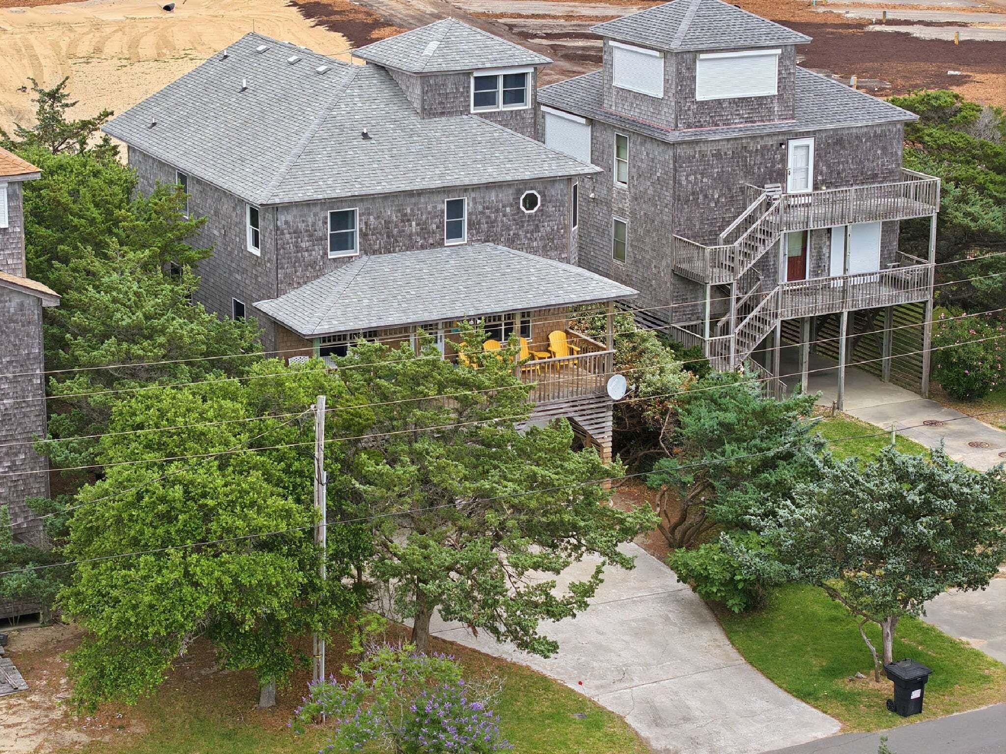 A multi-story house with a covered patio area and a staircase leading to an upper level.