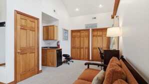 A compact living space with a kitchenette, a sofa, a desk with a chair, and a lamp. - Dog-friendly house short walk from beach with pool table & WiFi (Frisco)