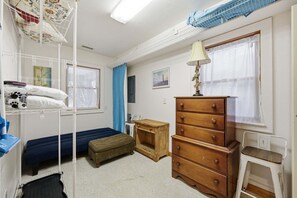 A bedroom with bunk beds, a dresser, a nightstand, and a lamp.