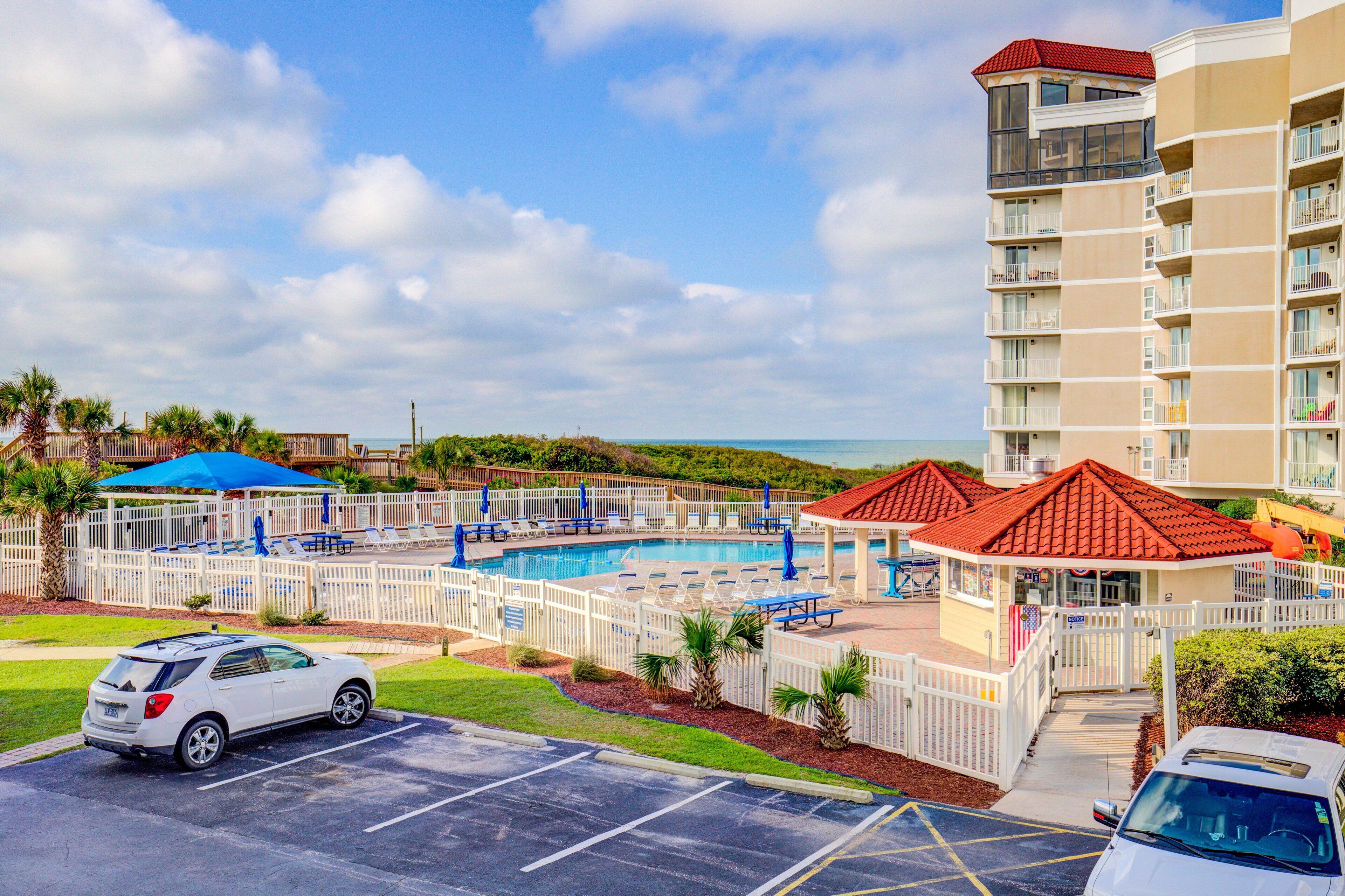 Hotel med swimmingpool, udendørs siddepladser og parkeringsareal.