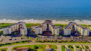 Un complex hoteler a la costa amb diversos edificis, zones d'aparcament i vistes a la platja.