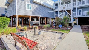 A multi-story building with a covered outdoor area, a barbecue grill, and a bench. - Sandvillas C1: 2nd-Floor | Balcony | Pool (Ocean Isle Beach)