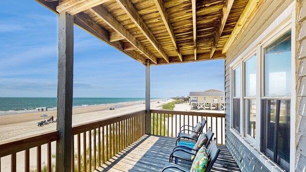Une terrasse en bois offrant une vue sur la plage et l’océan.