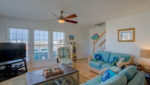 A living room with a television, a sofa, a chair, and a ceiling fan. - Luxe ocean-view beach estate - amazing views, private pool, hot tub & elevator (North Topsail Beach)