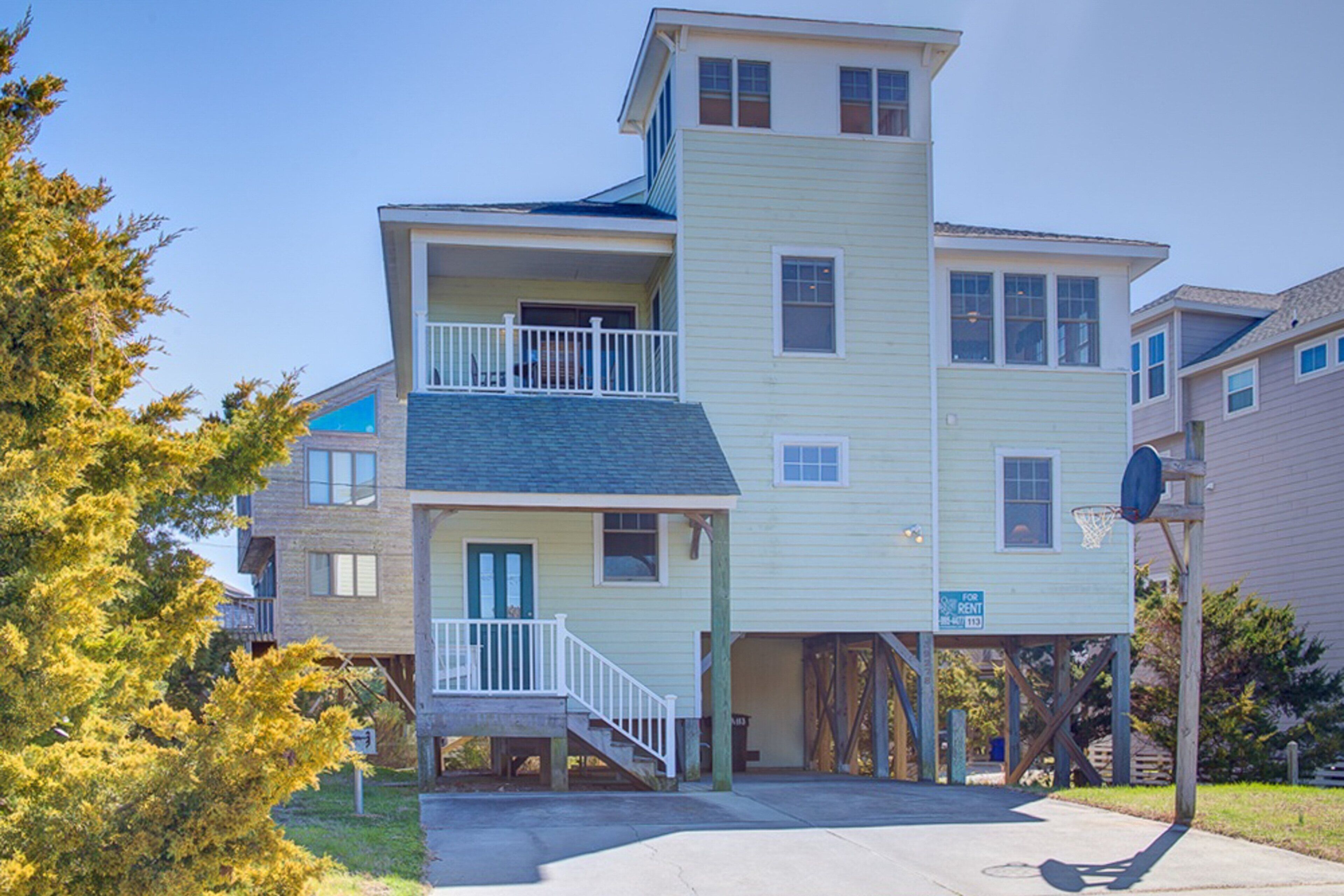 A multi-story residential building with a balcony, a garage, and a basketball hoop.