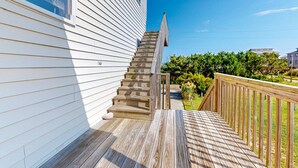Eine Holzterrasse mit einer Treppe, die zu einem weißen Haus führt.