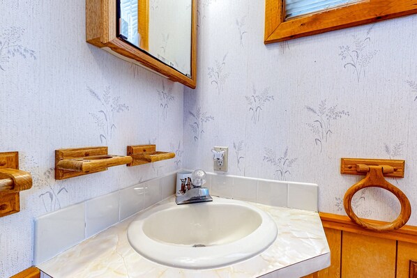 A bathroom with a marble sink, wooden towel racks, a toilet with a wooden seat, and a mirror with a wooden frame.
