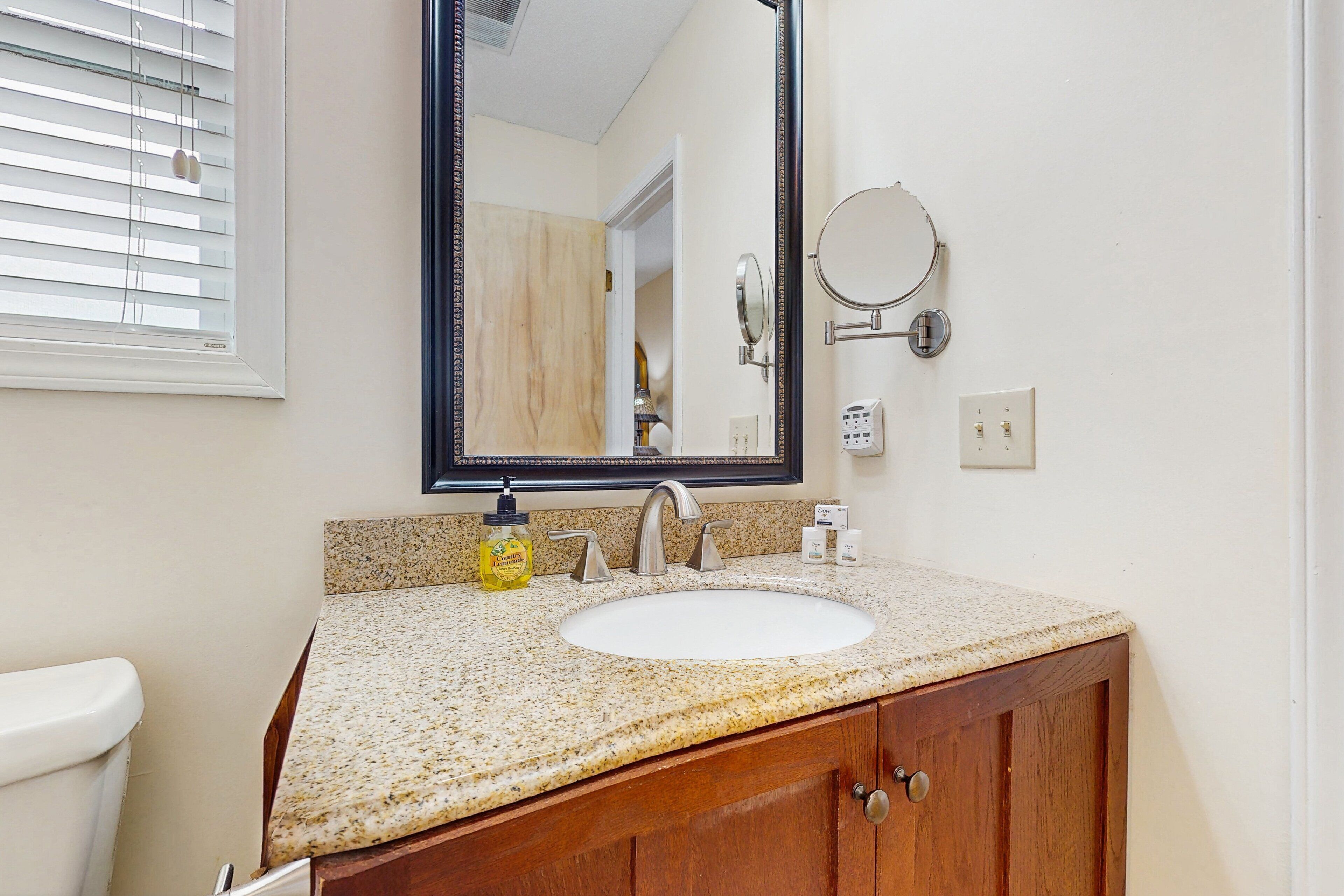 A bathroom with a white sink, wooden vanity, and a large mirror.