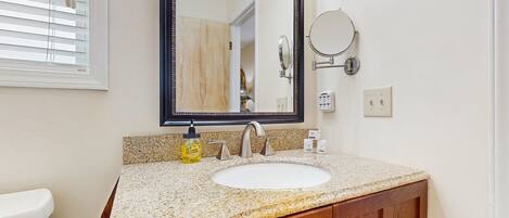 A bathroom with a white sink, wooden vanity, and a large mirror.