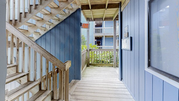 Una scala di legno conduce a un balcone con una parete esterna blu e una finestra.