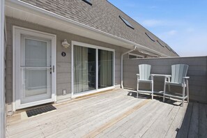 A covered deck with a sliding glass door, a small outdoor seating area with chairs, and a mailbox.