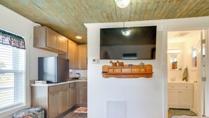 A modern kitchen with wooden cabinets, a built-in TV, and a small wooden cabinet with decorative items. - Pet-Friendly Farmhouse Suite w/ Patio in Vaughn! (Vaughn)