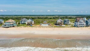 A beachfront property with multiple houses, a sandy beach, and a view of the ocean. - Beachfront home with pool, private hot tub, beach access & lovely views (North Topsail Beach)