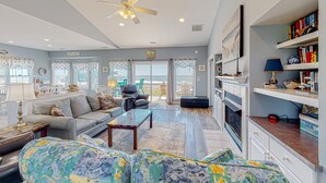 A spacious living room with a sofa, coffee table, and a ceiling fan. - Beachfront home with pool, private hot tub, beach access & lovely views (North Topsail Beach)