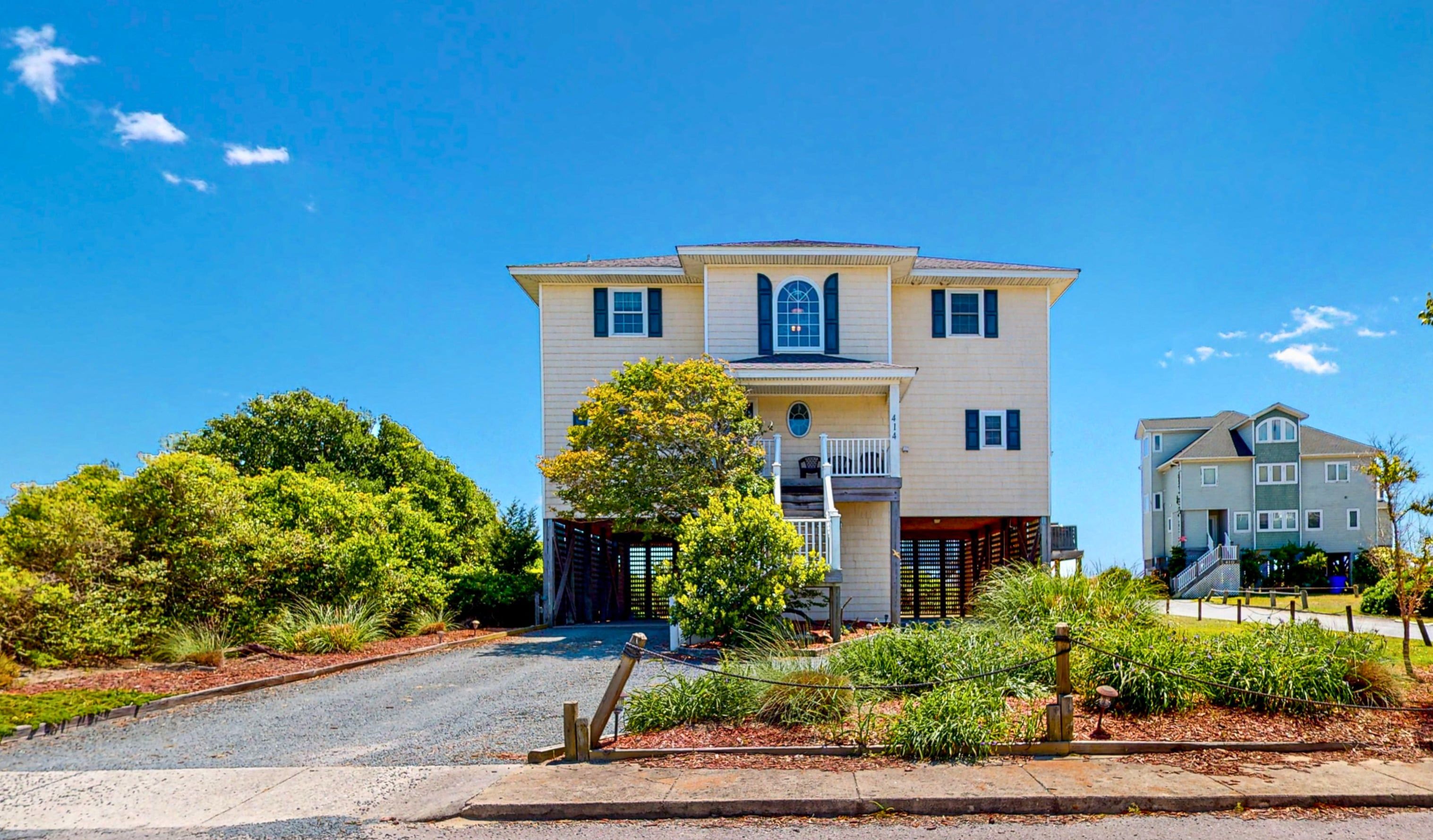 A two-story house with a front porch, a garage, and a driveway leading to the entrance.