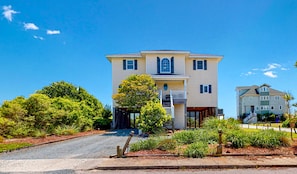 A two-story house with a front porch, a garage, and a driveway leading to the entrance.