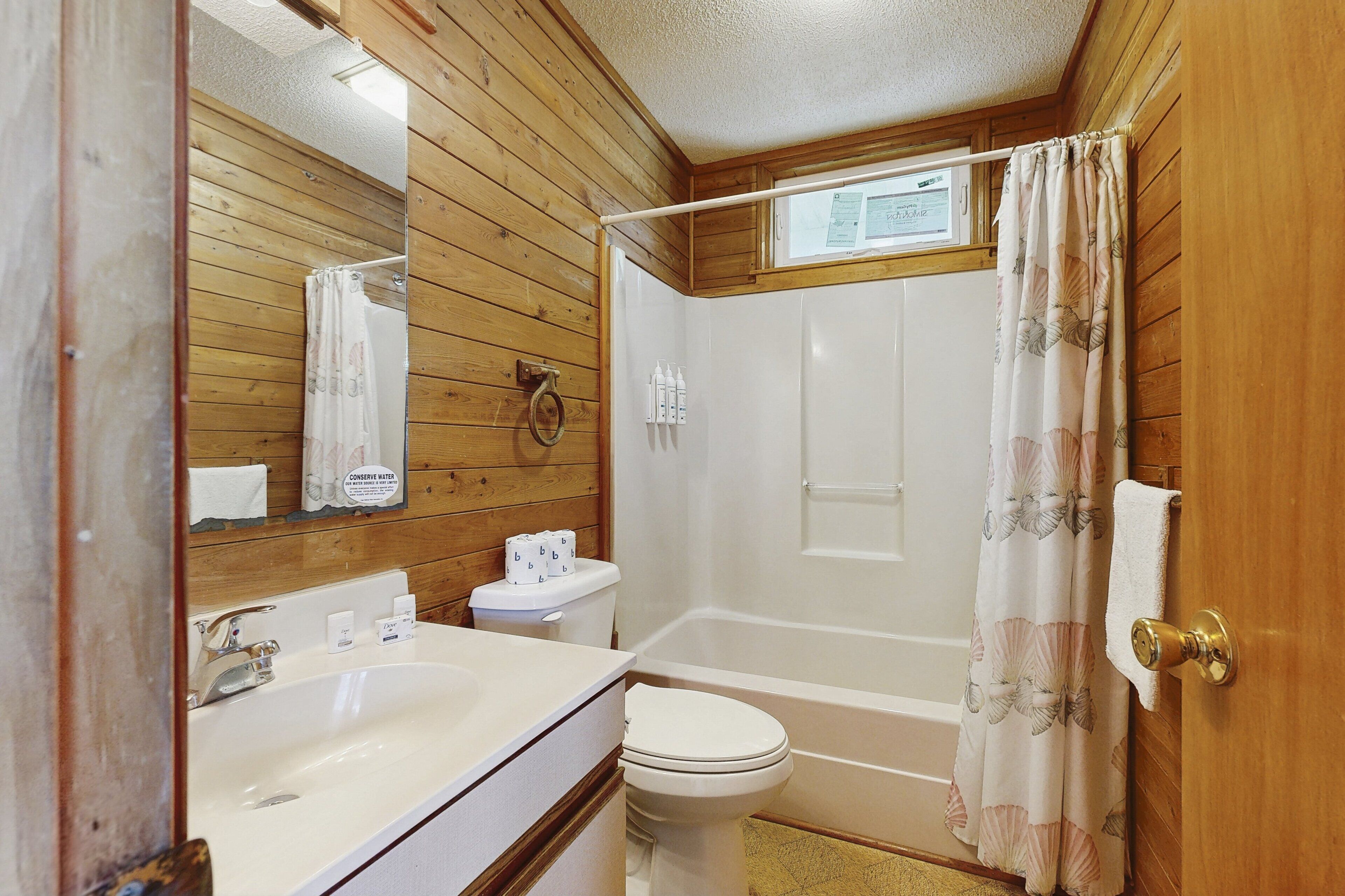 A bathroom with wooden paneling, a white sink, toilet, and bathtub.