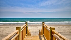 Una passerella in legno conduce a una spiaggia con vista libera sull'oceano.