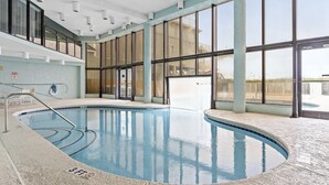 Una piscina interior con paredes de vidrio transparente, un indicador de profundidad de 3 pies e iluminación empotrada en el techo.
